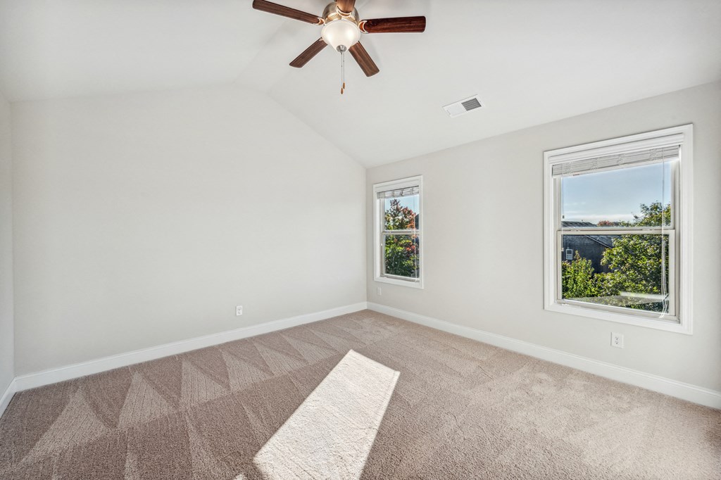 Primary bedroom with carpet and ceiling fan.