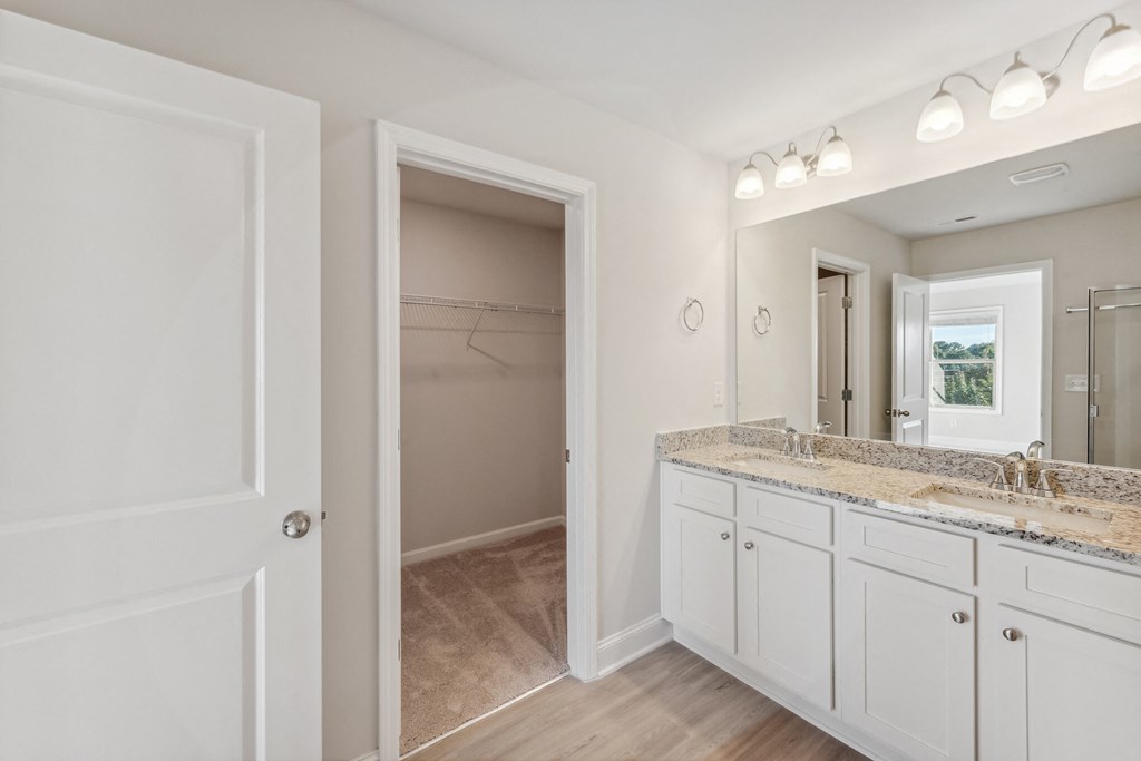primary bathroom with double vanity and large walk-in closet.