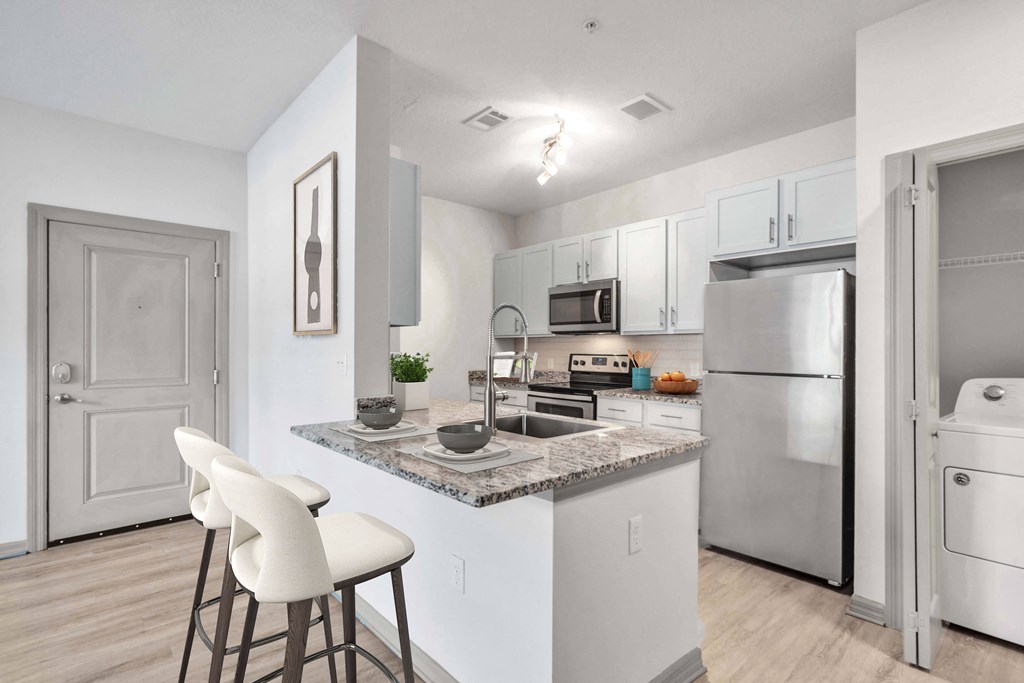 A kitchen with a white countertop and white chairs.