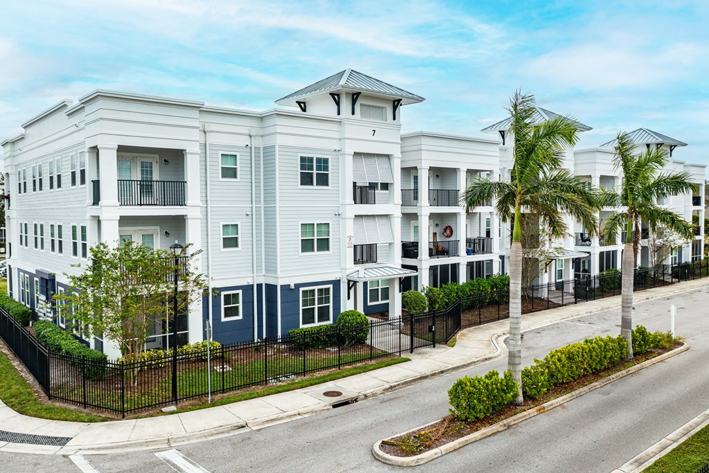 A row of modern townhouses with balconies and black fences.