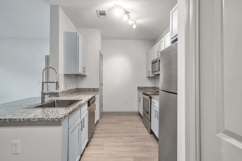 A kitchen with a marble countertop and stainless steel appliances.