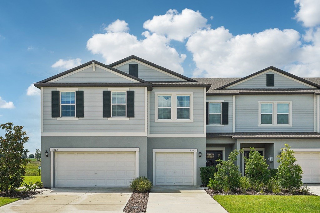a house with two garage doors and a sidewalk in front of it