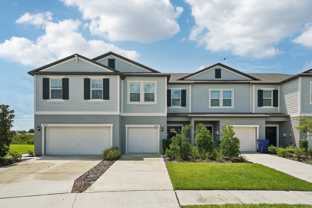 a blue house with two garage doors and a lawn