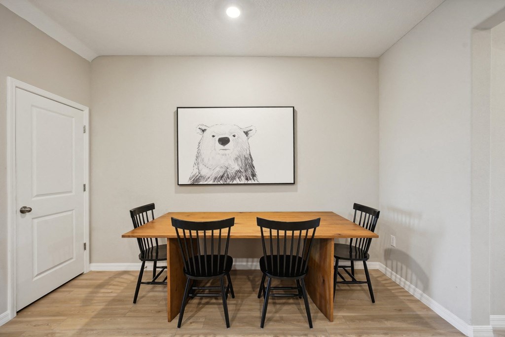 a dining room with a table and chairs and a painting of a bear