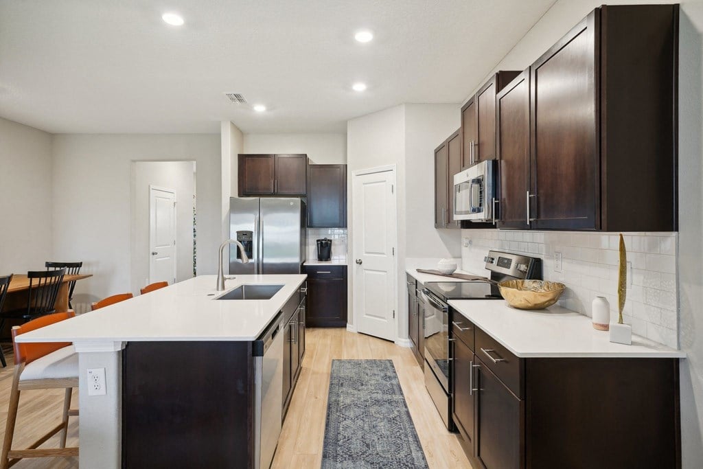 a large kitchen with stainless steel appliances and white counter tops