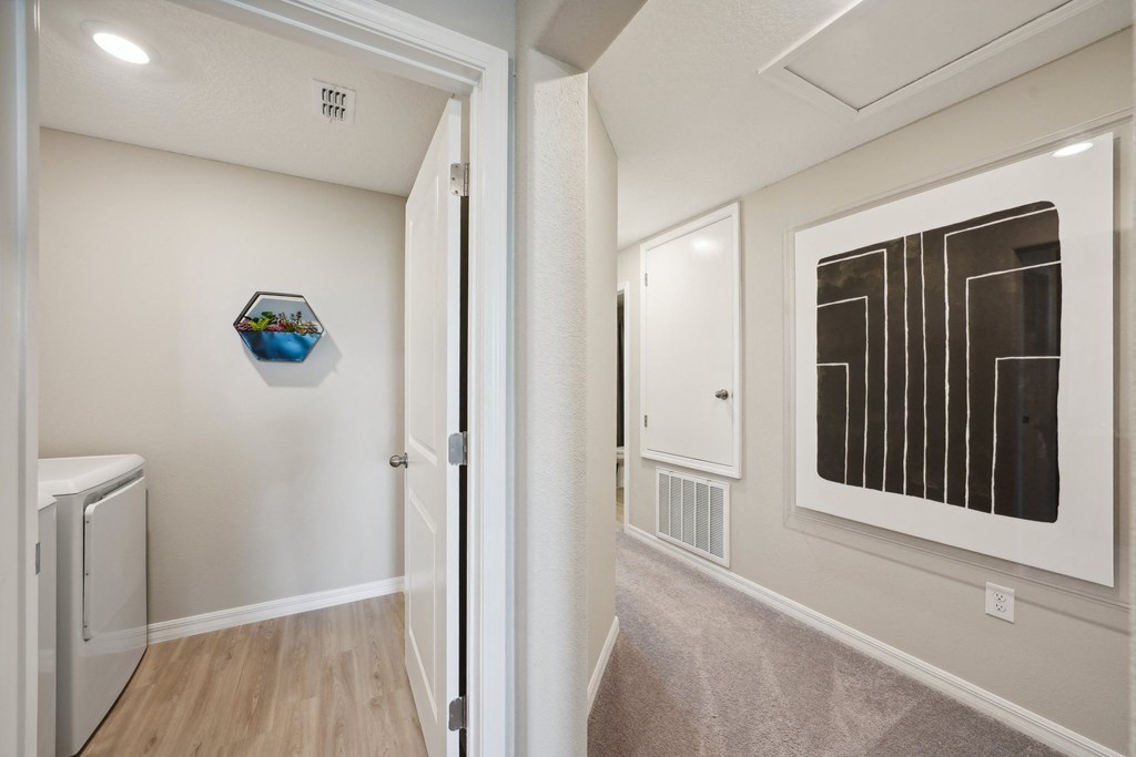 a hallway with a painting on the wall and a door to a laundry room
