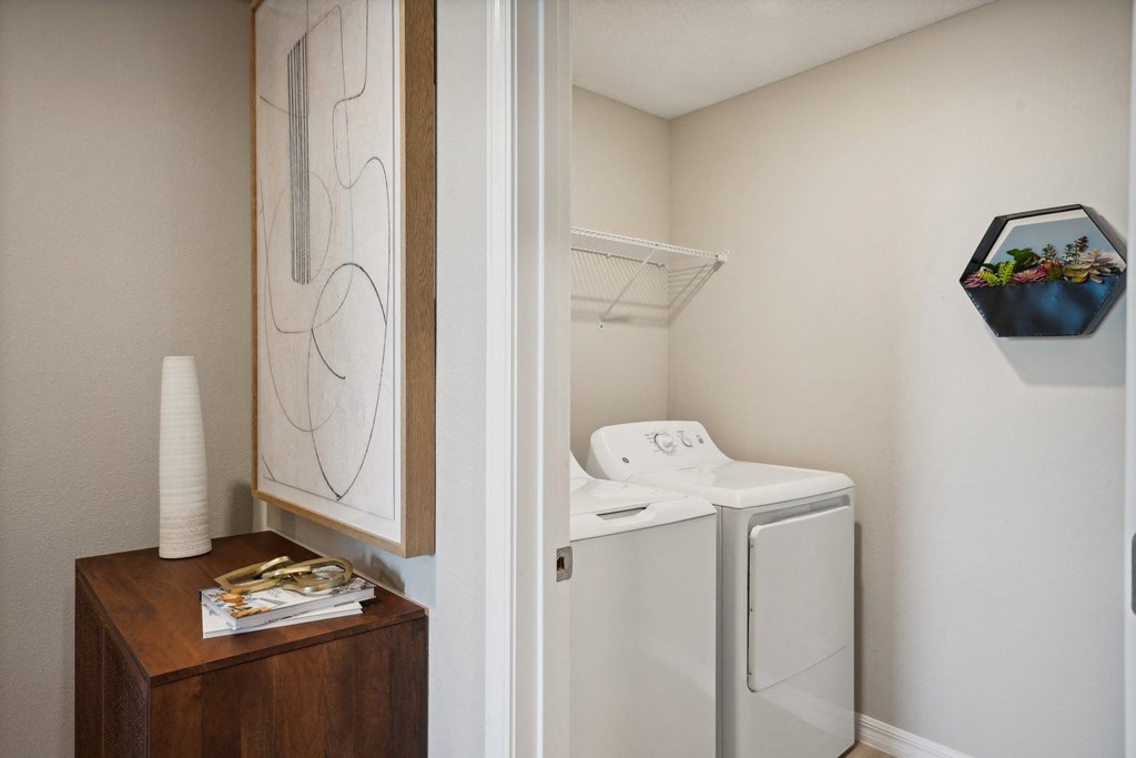 a small laundry room with a washer and dryer and a wooden dresser
