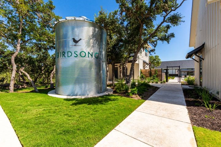 a water tank sits in the grass outside of a building