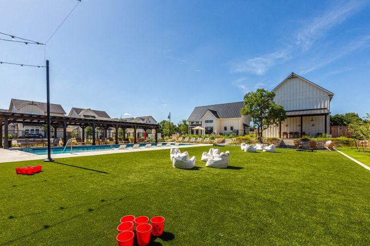 a backyard with a pool and chairs on the grass