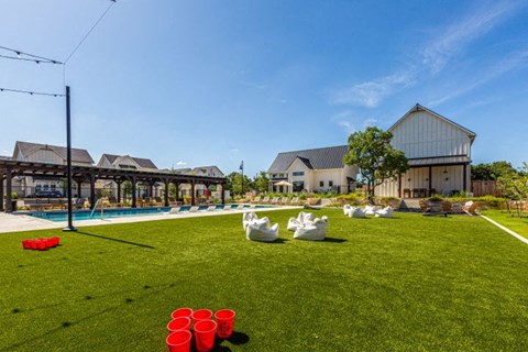 a backyard with a pool and chairs on the grass