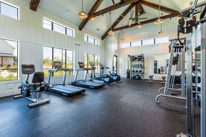 a gym with weights and cardio equipment and windows