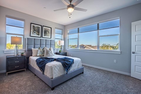 A bedroom with a large bed and a ceiling fan.