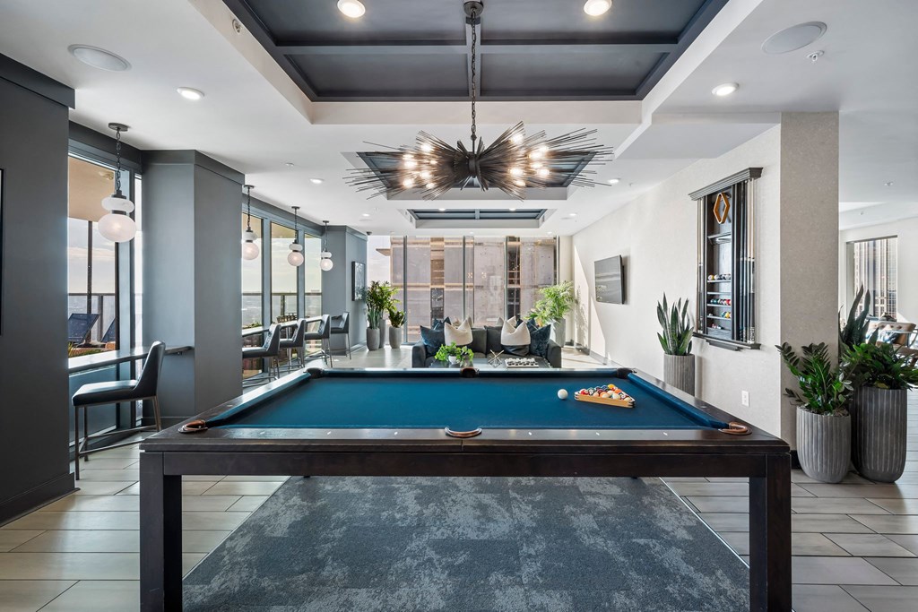 a pool table in a clubhouse with a view of a dining room and a bar
