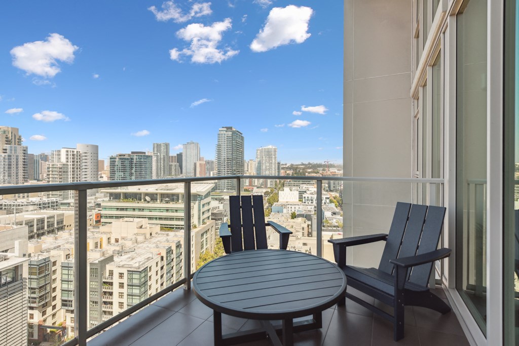Balcony with a table and chairs and a view of the city at K1 Apartments, San Diego, CA