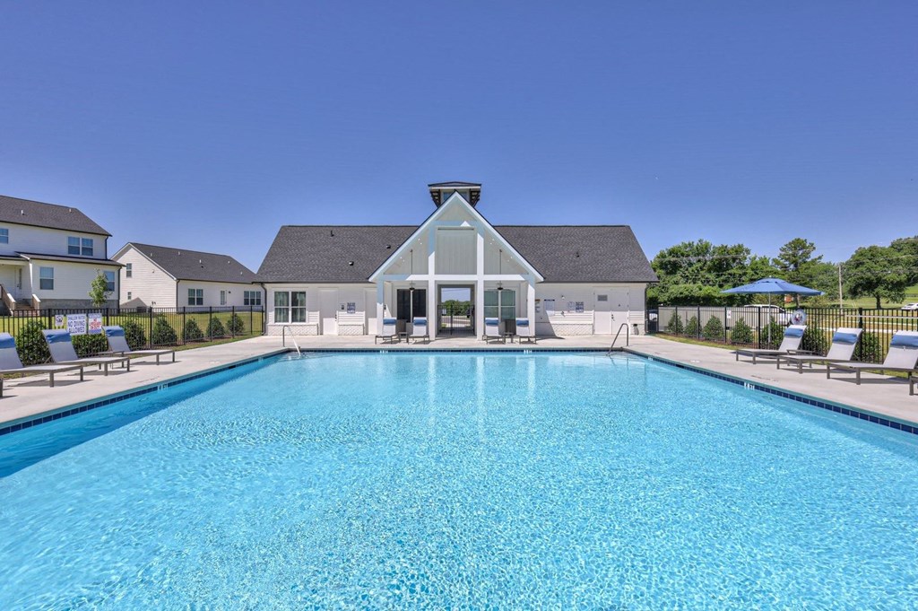 a large swimming pool with a house in the background