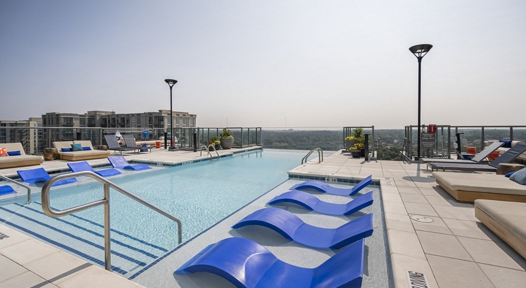 a swimming pool with blue lounge chairs on top of a building