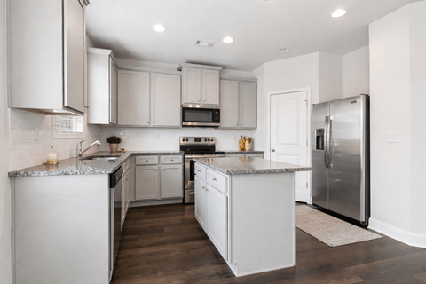 A modern kitchen with white cabinets and stainless steel appliances.