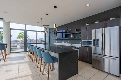 A modern kitchen with a long bar and stainless steel appliances.