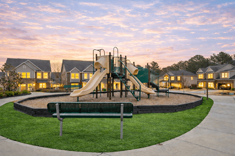 A playground with a slide and a bench in the foreground.