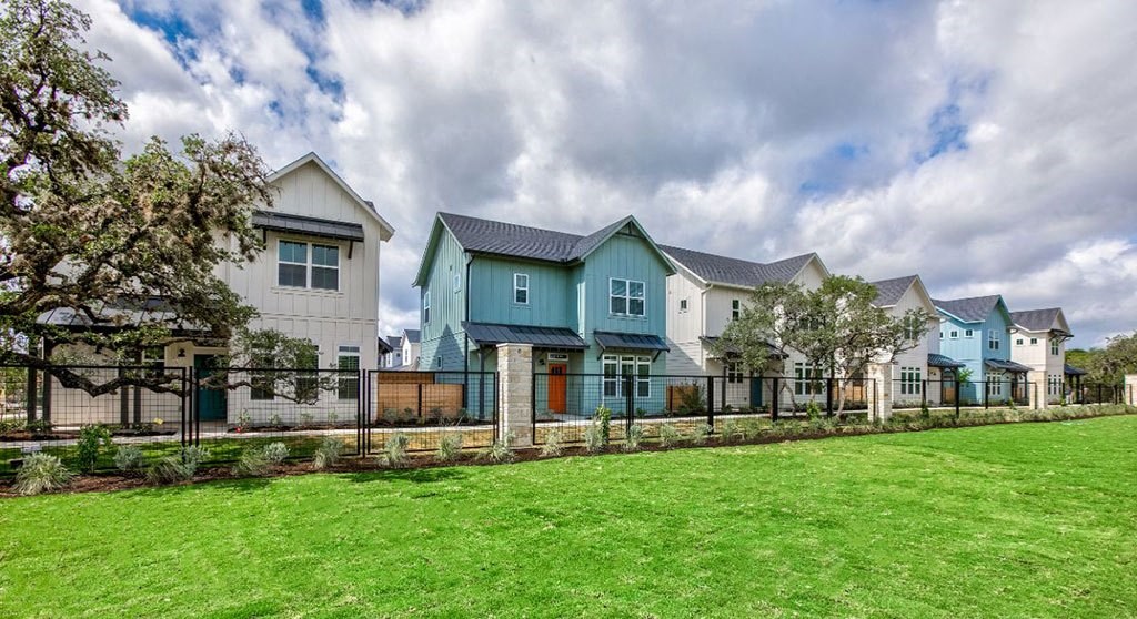 a row of houses in front of a green field