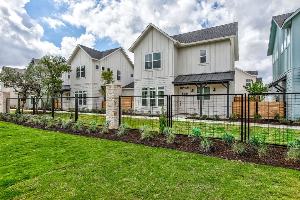 a large white house with a yard and a fence