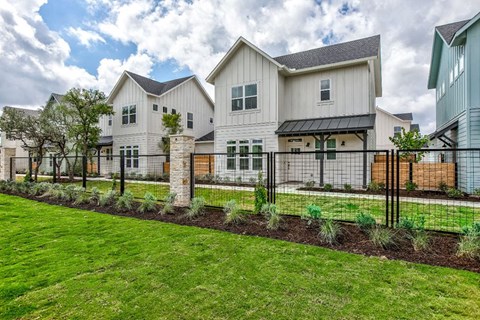a large white house with a yard and a fence