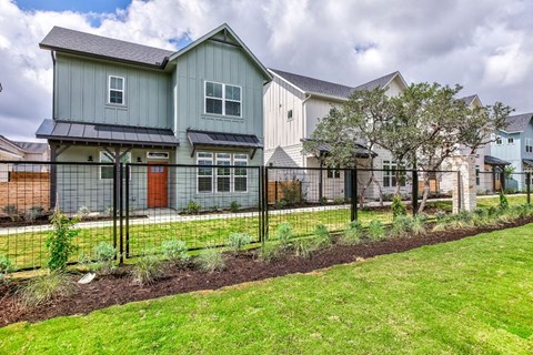 the front of a house with a yard and a fence