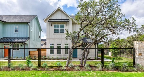 a house with a fence and a tree in front of it