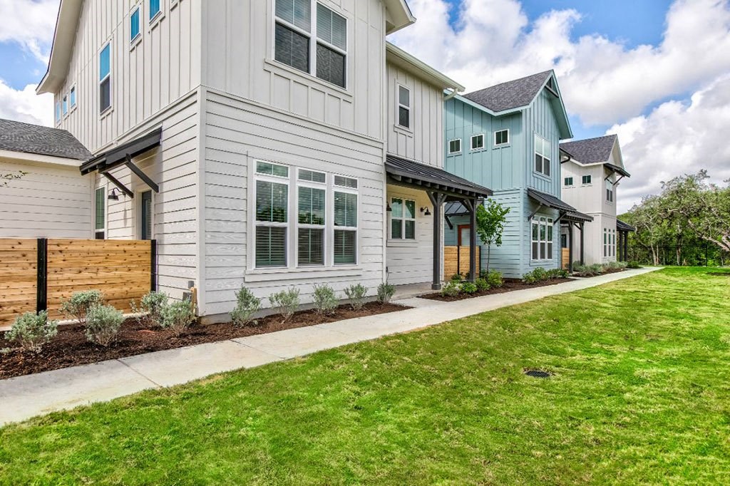 a white and blue house with a sidewalk and grass