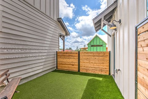 a yard with a wooden fence and a green house in the distance