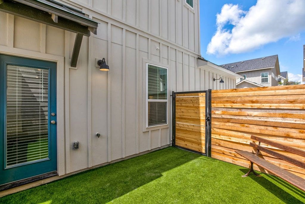 a backyard with a wooden fence and a house with a blue door