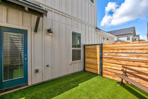 a backyard with a wooden fence and a house with a blue door