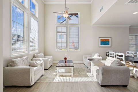 A living room with white furniture and a ceiling fan.