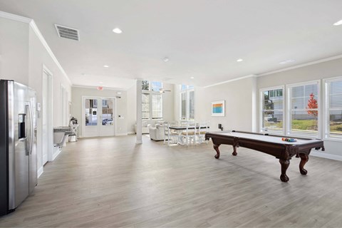 A spacious kitchen with a pool table and a refrigerator.
