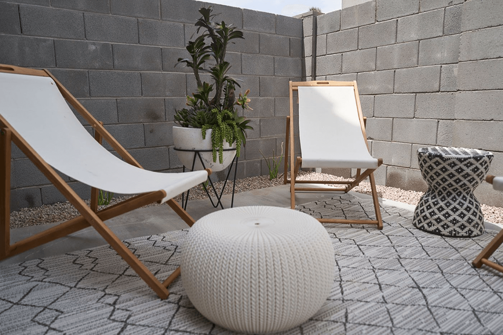 a patio with two chairs and a white ottoman and a mirror and plants at Novella Biltmore, Phoenix, AZ