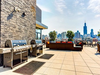 Community Outdoor Grilling Area at The Madison at Racine Outdoor grilling area with lounge seating and a skyline view at The Madison at Racine, Chicago, 60607 - Photo Gallery 3