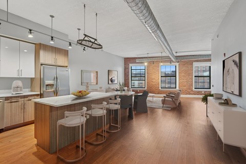 A kitchen with white chairs and a white table with a bowl of fruit on it.