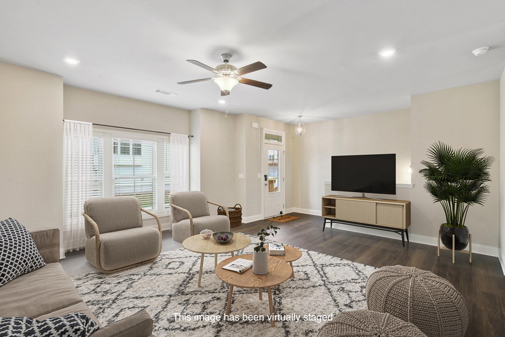 a living room with a ceiling fan and a tv