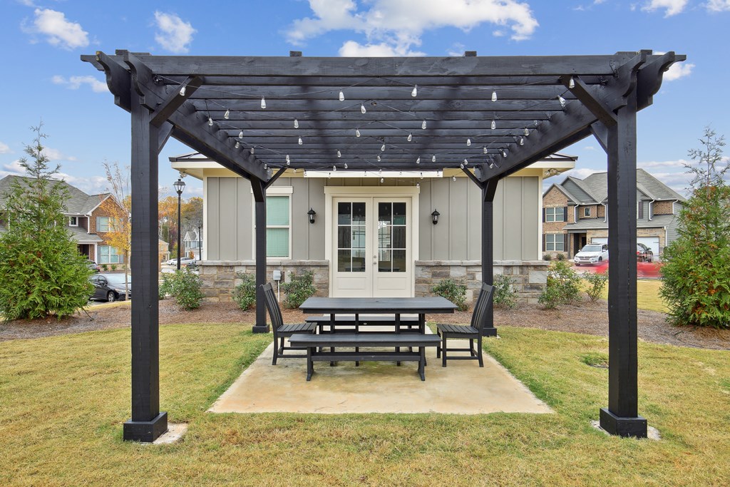 a picnic area with a table and chairs under a pergola