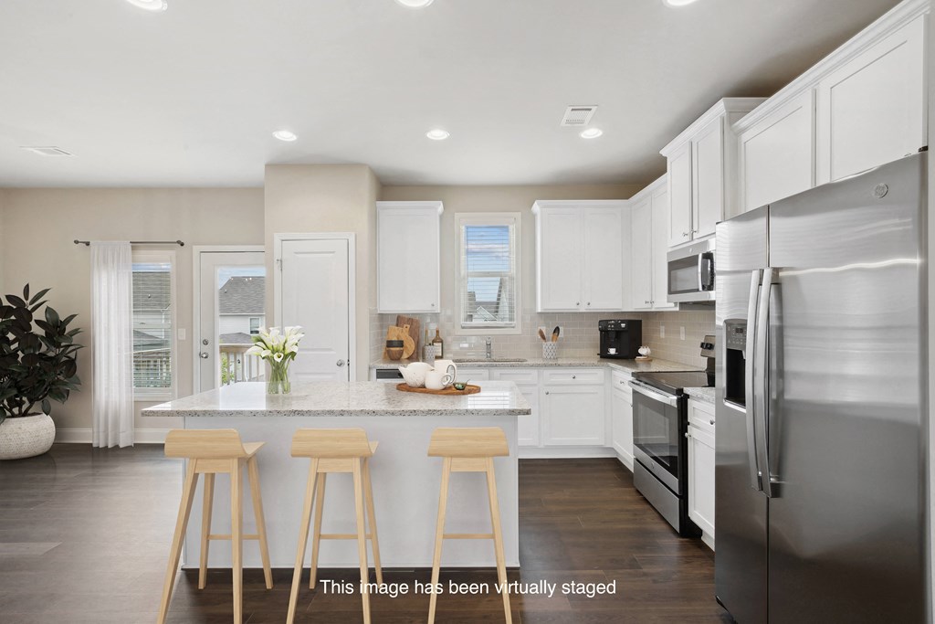 a large kitchen with white cabinets and stainless steel appliances