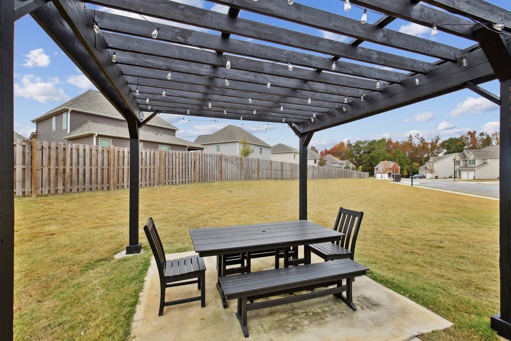a patio with a picnic table and chairs under a pergola