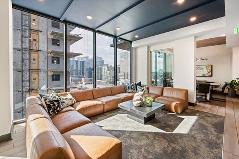 a living room with leather couches and a table    and large windows