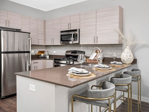a kitchen with stainless steel appliances and a counter with chairs