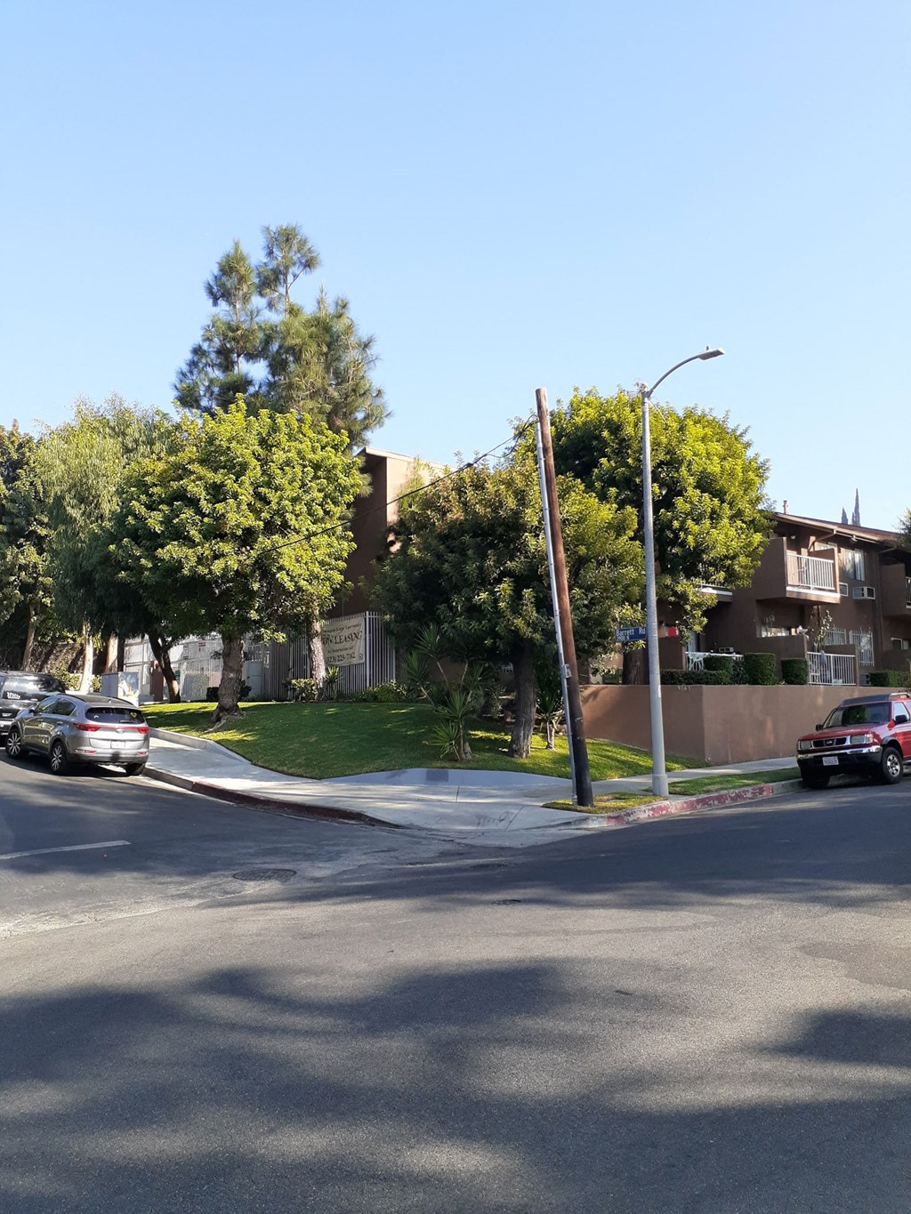 the corner of a street with cars parked in front of an apartment building