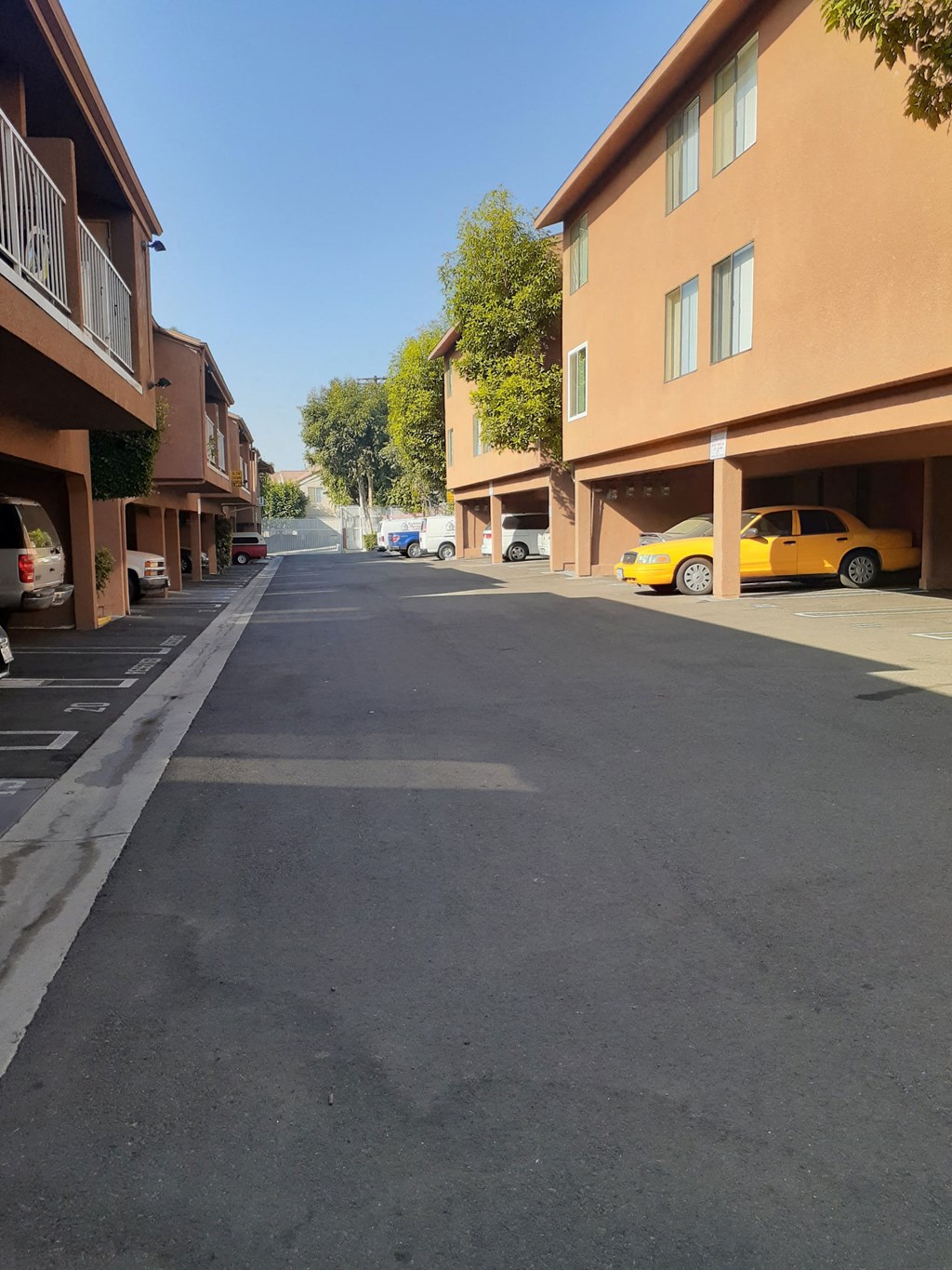 a city street with buildings on both sides and a yellow car parked in the distance