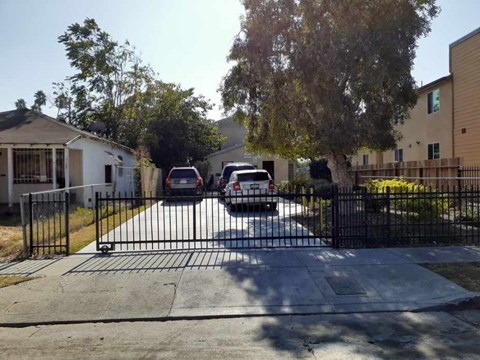 A black gate blocks the entrance to a driveway.