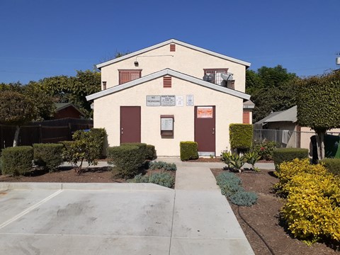 A building with a sign on it and bushes in front.