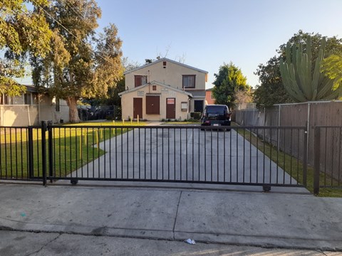 A black gate blocks the driveway to a house.