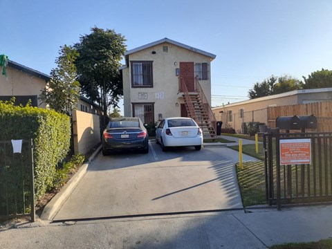 Two cars are parked in front of a house with a sign that reads "The Artist's Alley.".