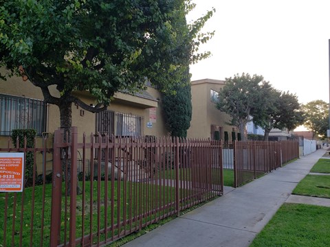 A sign is posted on a fence in front of a building.